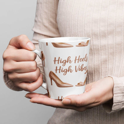 Person holding white ceramic latte mug with high heels design and "High Heels High Vibes" text