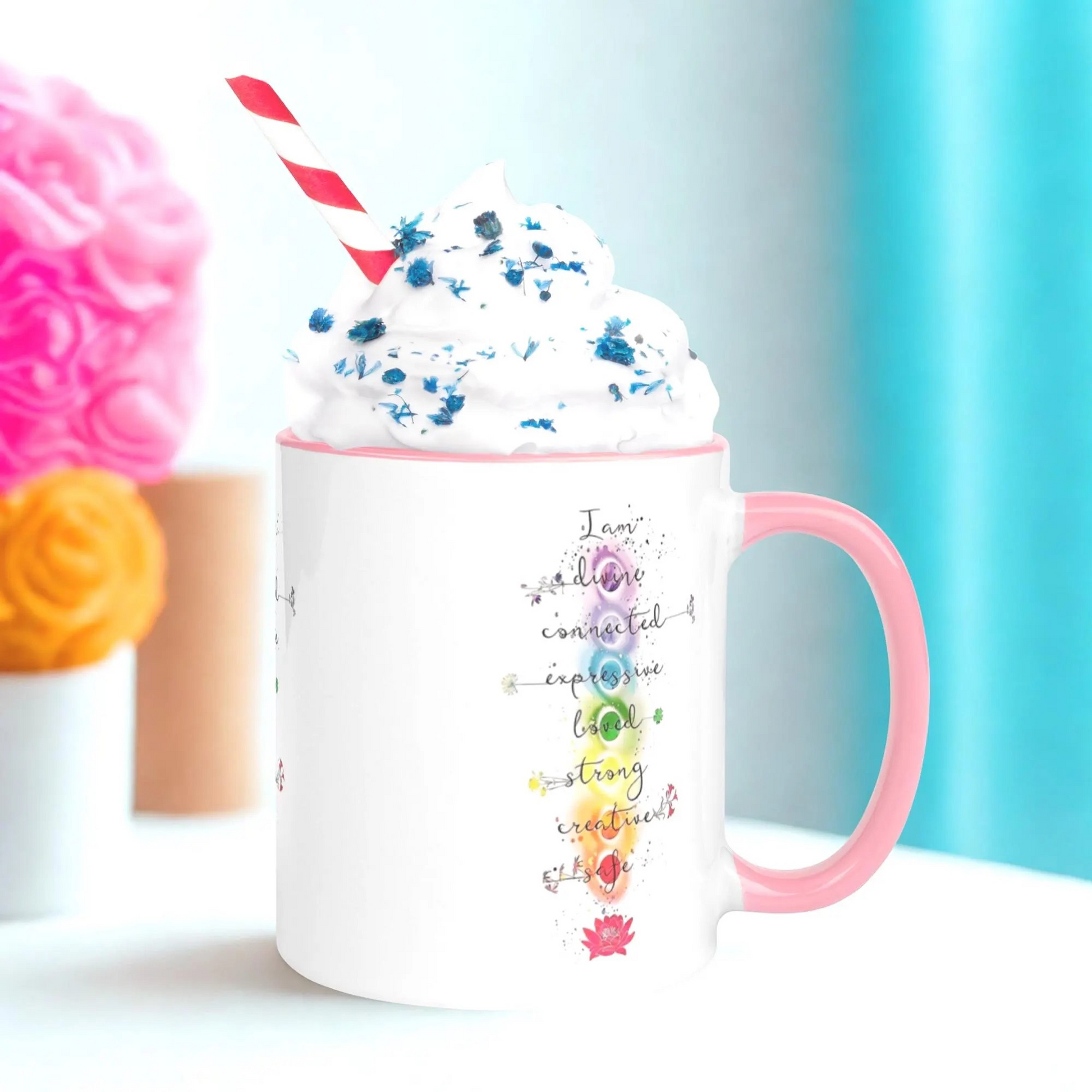 Motivation Chakra Mug ceramic cup with colorful chakra symbols and pink handle filled with whipped cream and blue sprinkles
