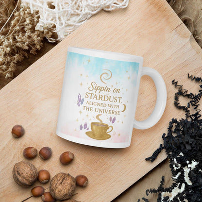 white ceramic Sippin on Stardust Coffee Mug with celestial design and golden text on wooden tray with nuts and decorative elements