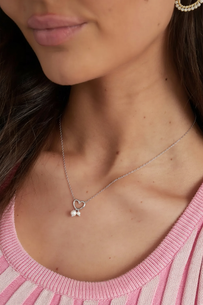 Model draagt minimalistische zilverkleurige ketting met hartje...