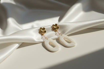 Minimalistische oorbellen met parelmoer look op satijnen achtergrond