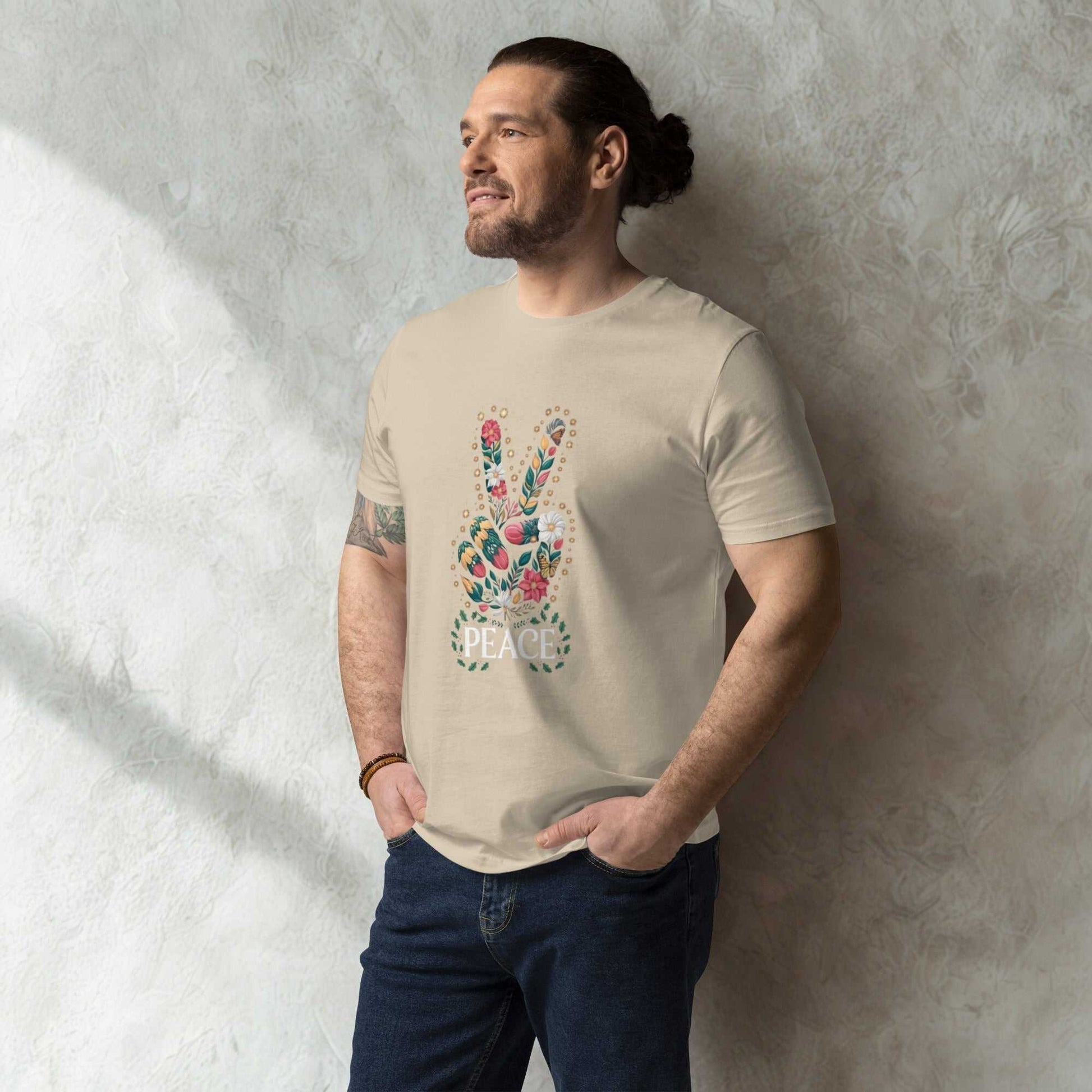 Man wearing beige unisex organic cotton T-shirt with a colorful peace sign graphic, standing against a textured wall
