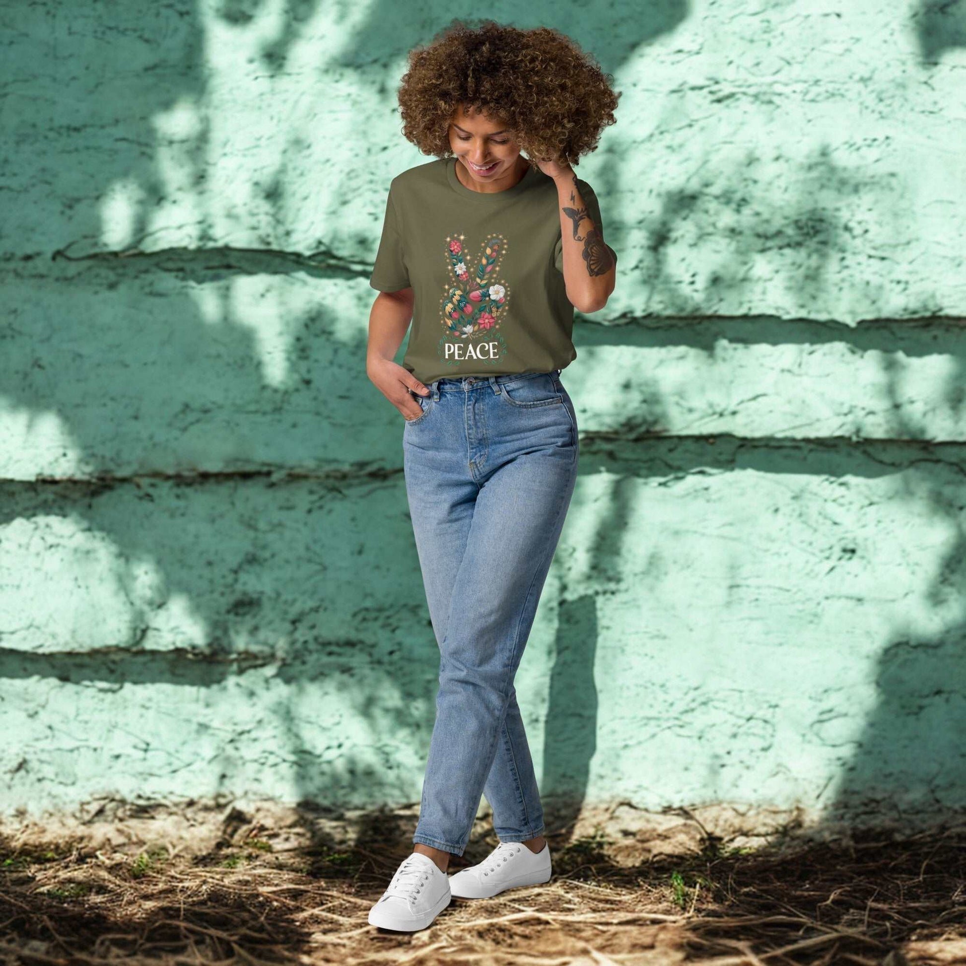 woman wearing green unisex organic cotton t-shirt with peace graphic and blue jeans outdoors