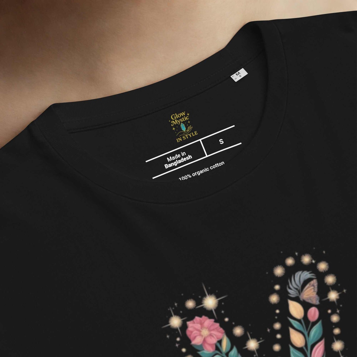 close-up of black unisex organic cotton t-shirt neckline with printed size label and floral design