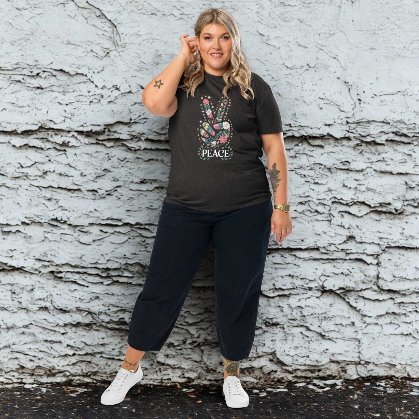 plus size woman wearing black unisex organic cotton t-shirt with peace hand sign design and black pants against textured wall background
