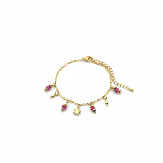 Goudkleurig rvs armbandje met zonnestralen bedeltje en fuchsia kralen op een heldere witte achtergrond.