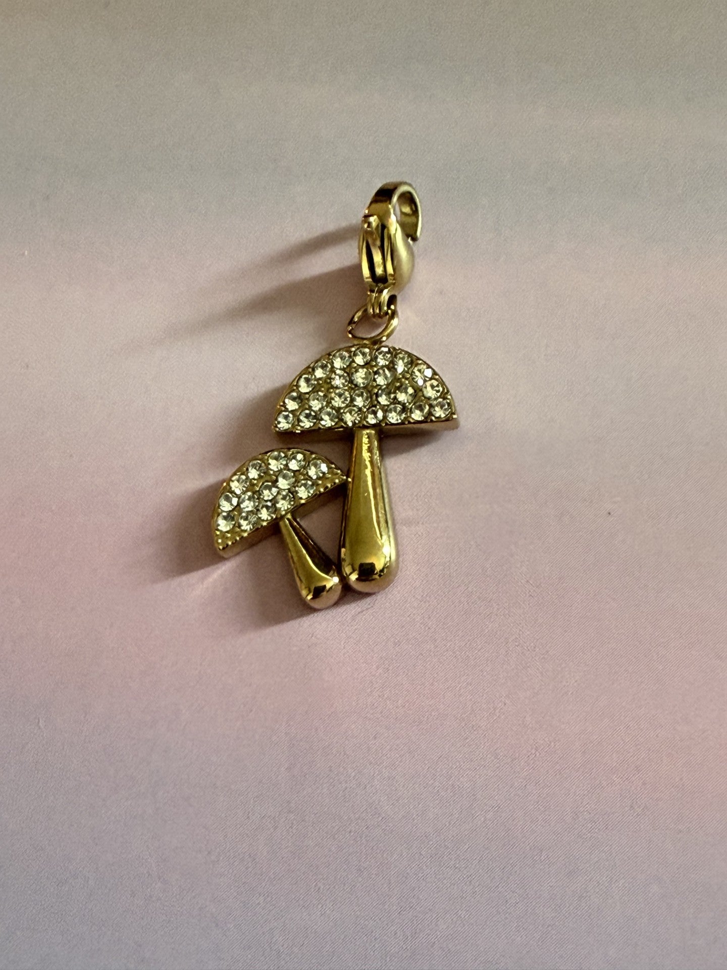 Luxe goudkleurige RVS paddenstoel bedel met fonkelende strass voor armband of ketting op gekleurde achtergrond.