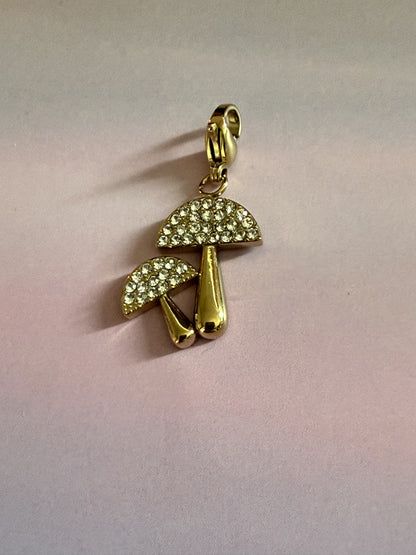 Luxe goudkleurige RVS paddenstoel bedel met fonkelende strass voor armband of ketting op gekleurde achtergrond.