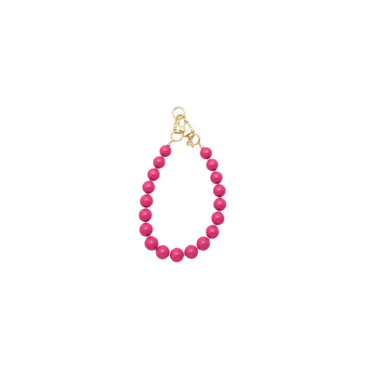 Handgemaakte fuchsia roze phone charm met gouden details op een witte achtergrond.