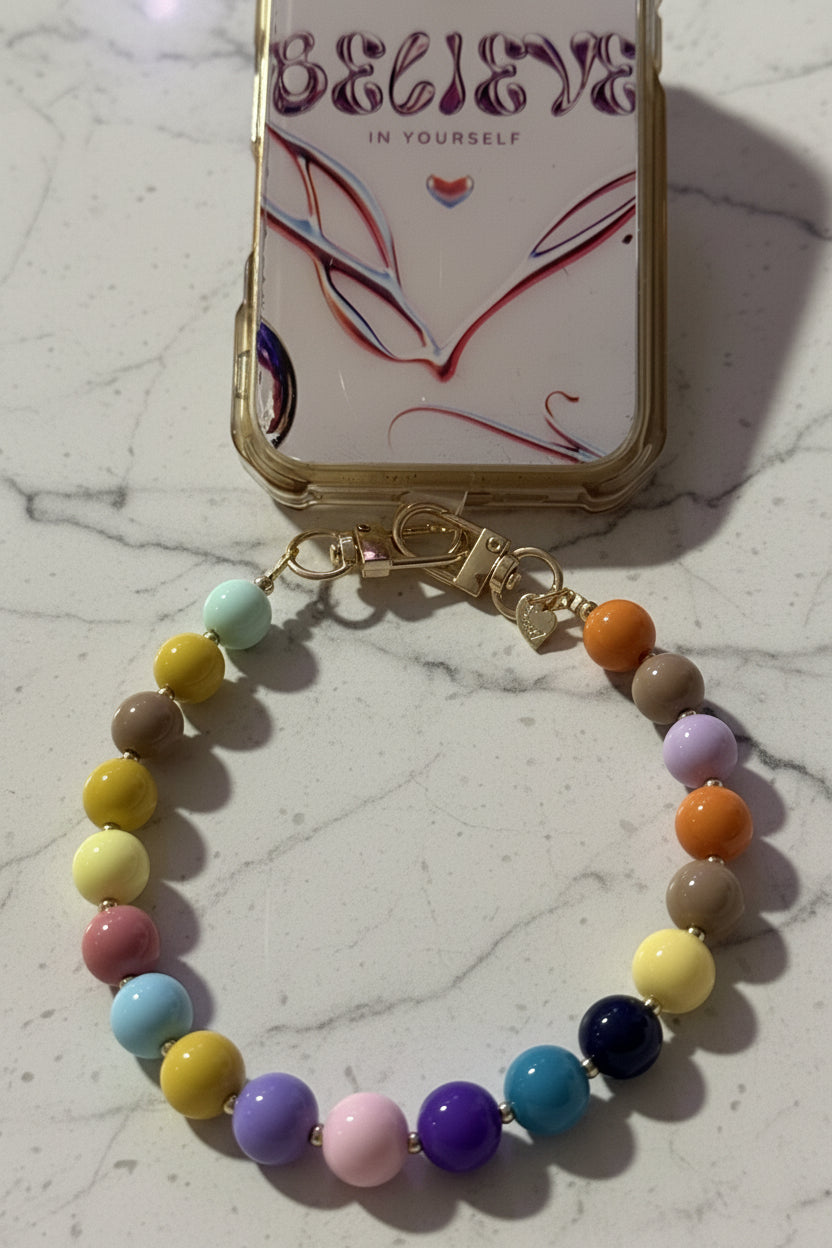 "Kleurrijke Multi-color phone charm bevestigd aan een telefoonhoesje met de tekst 'Believe in yourself'."