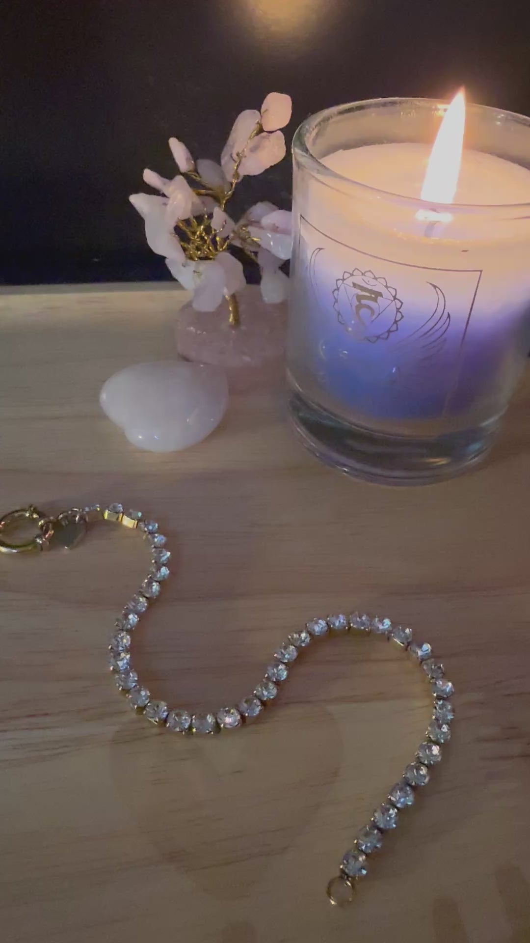 Video van de kristallen Divine Light armband die prachtig schittert in het licht, liggend op een houten tafel naast spirituele accessoires.