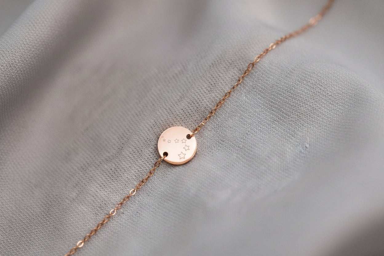 Rosé kleurige  troost armbandje met sterrenbedel op lichte stof