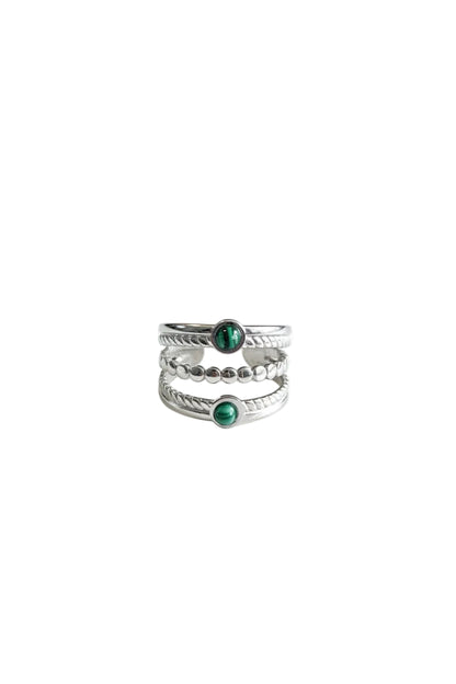 "Zilverkleurige RVS ring met een driedubbele band en twee ronde groene steentjes op een heldere witte achtergrond."