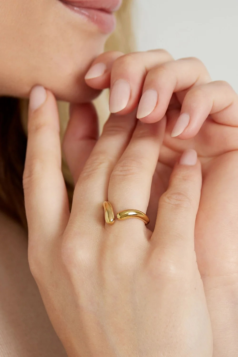 Model draagt gouden verstelbare organische ring aan de hand