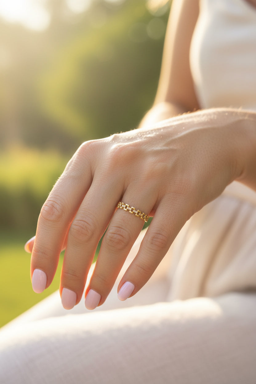 "Close-up van een vrouw in een elegante witte jurk die de goudkleurige RVS ring met kristallen op haar hand laat zien."