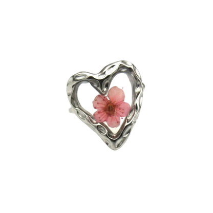 "Zilverkleurige RVS ring met een hartvormig design en een roze gedroogde bloem in het midden op een witte achtergrond."