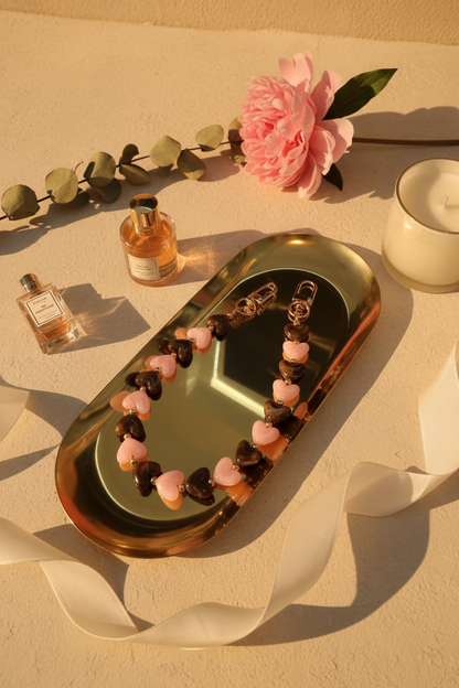 Glow Mystic in Style Bruin & Roze hartjes telefoonkoord op goudkleurige schaal met een lifestyle achtergrond.