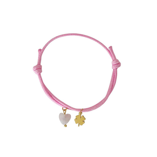 "Studiofoto van een roze waxkoord armbandje met een Rozenkwarts hartje en een goudkleurig klavertje vier bedeltje op een witte achtergrond."