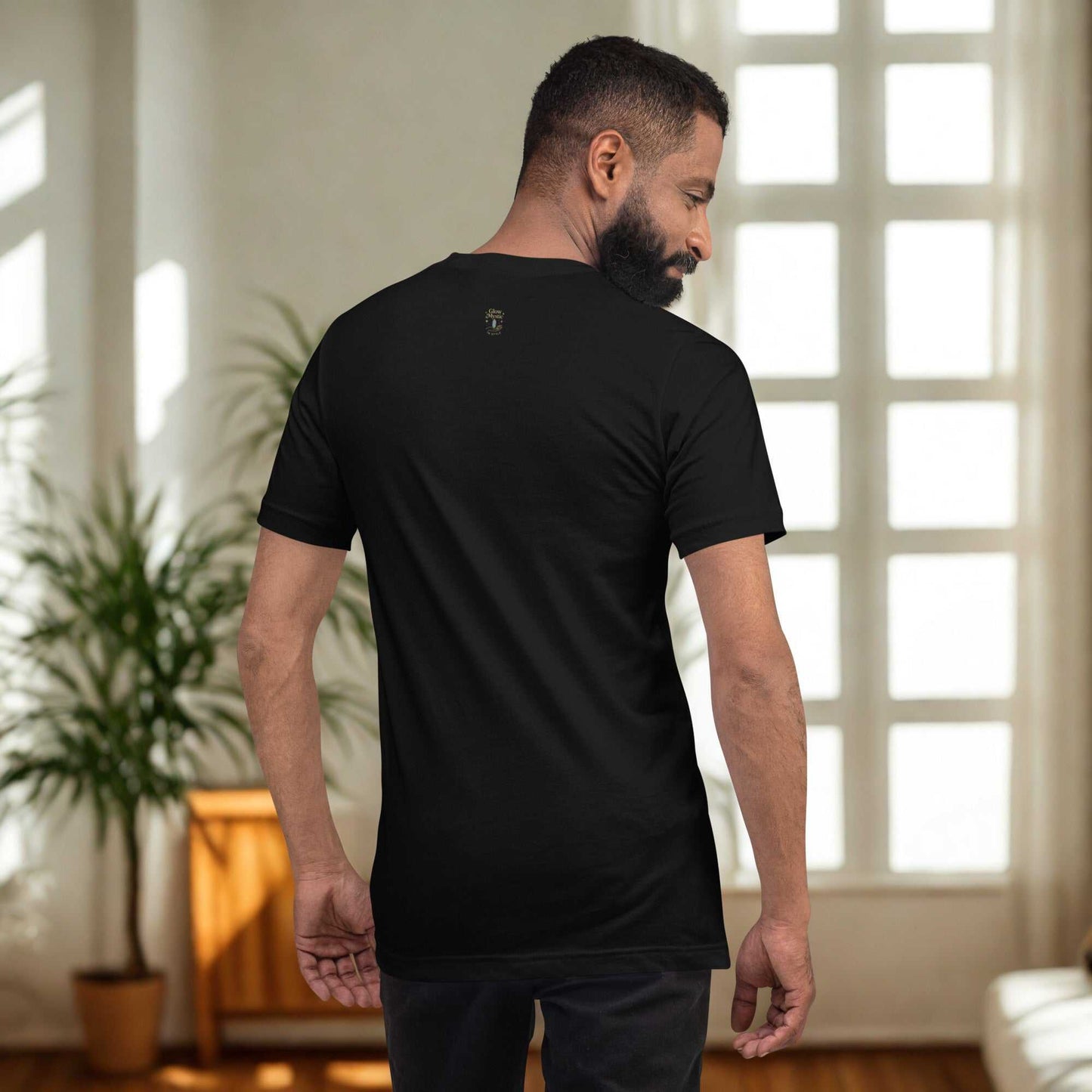 Man wearing black Celestial Glow Goddess T-Shirt with cosmic-inspired design shown from back in bright room