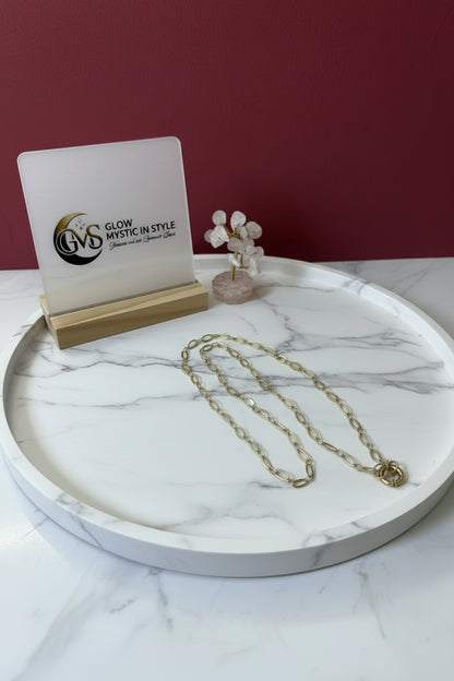 Tijdloze gouden damesketting van roestvrij staal voor dagelijks gebruik gepresenteerd op een marmerkleurige  schaal met display van Glow Mystic in Style
