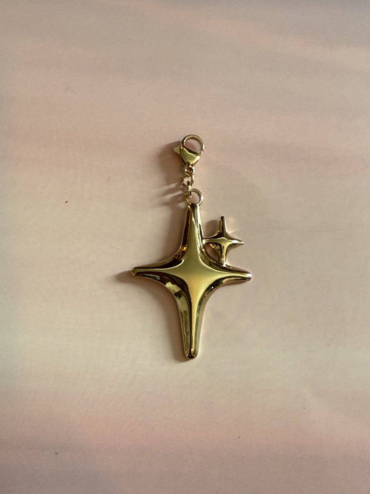 Luxe gouden RVS ster bedel van stainless steel voor ketting op gekleurde achtergrond.