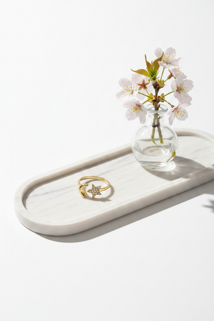 Sfeerbeeld van een langwerpige marmeren schaal met een ring en een vaasje bloemen