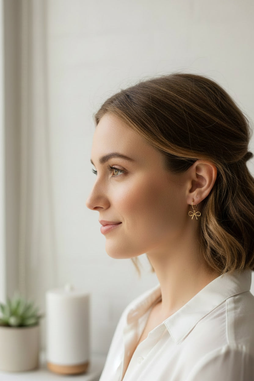 Ear party inspiratie met de goudkleurige RVS strikjes oorbellen gedragen in het oor door een model, gecombineerd met een chique minimalistische look.