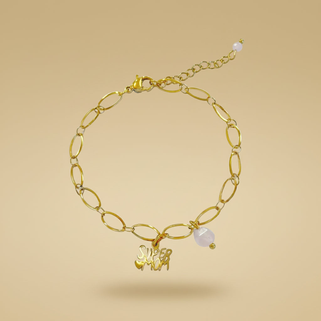 Goudkleurige schakelarmband met "supermom" bedel en parelmoer detail van Saint Clairmont op een beige achtergrond