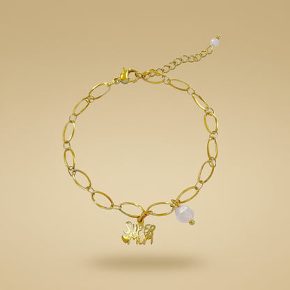 Goudkleurige schakelarmband met "supermom" bedel en parelmoer detail van Saint Clairmont op een beige achtergrond