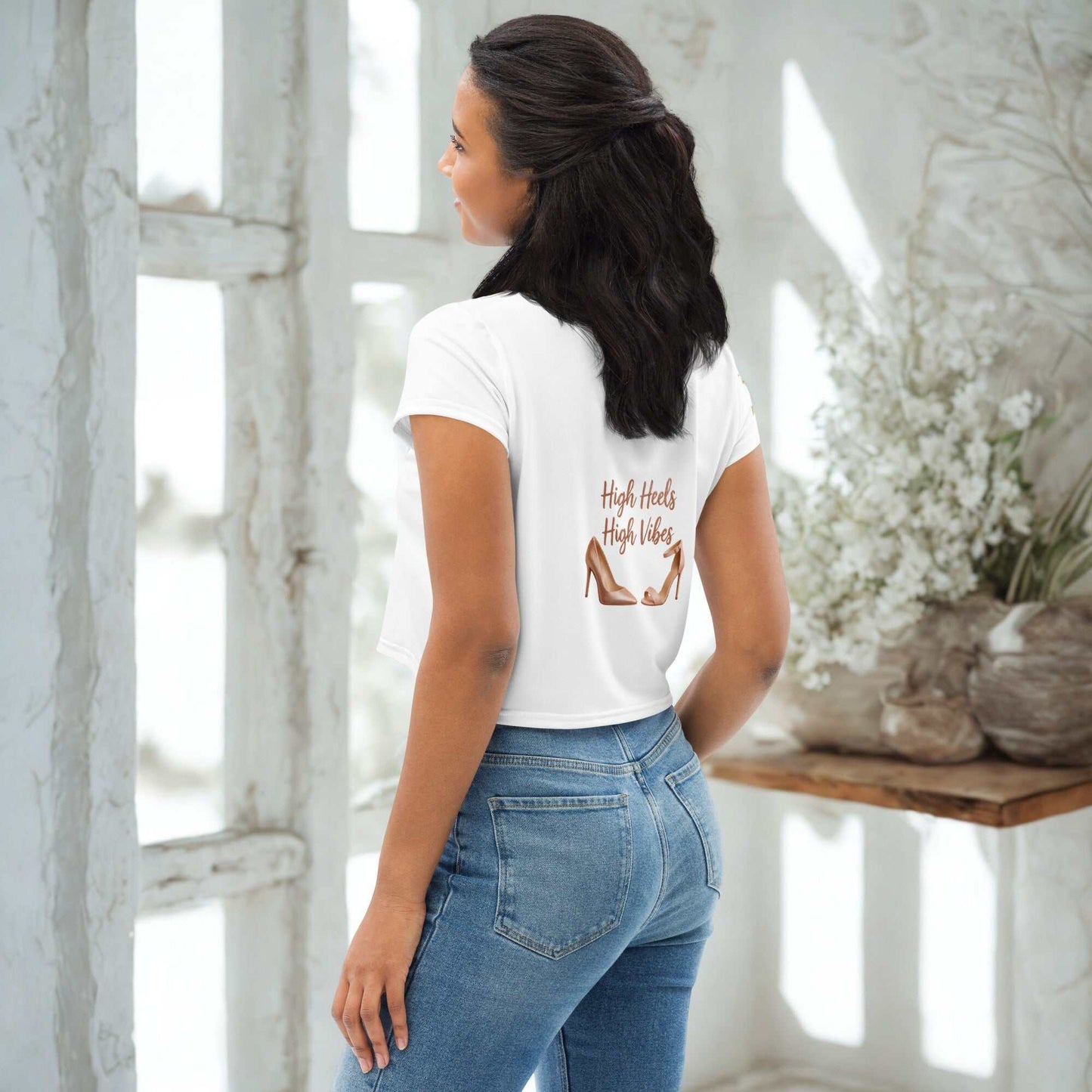 Woman wearing white High Heels High Vibes Crop Top with graphic and blue jeans standing indoors