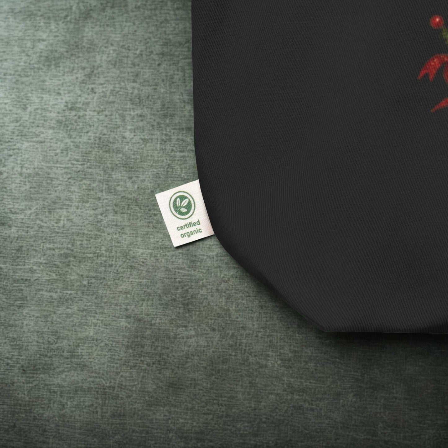 close up of black eco tote bag corner with certified organic label on textured green surface