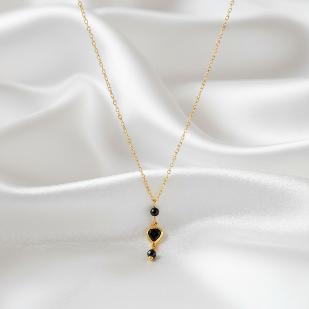 Detail van een elegante ketting met zwarte toermalijn en kristal hartje op zachte stof.