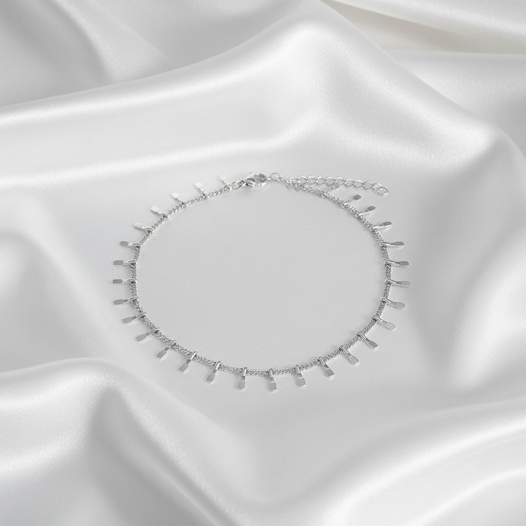 Zilver en goudkleurige trendy enkelbandjes naast elkaar op satijnen ondergrond