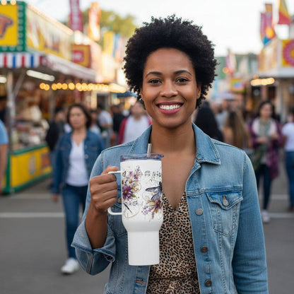 Woman holding a Dragonfly Dreams travel mug with handle at an outdoor market