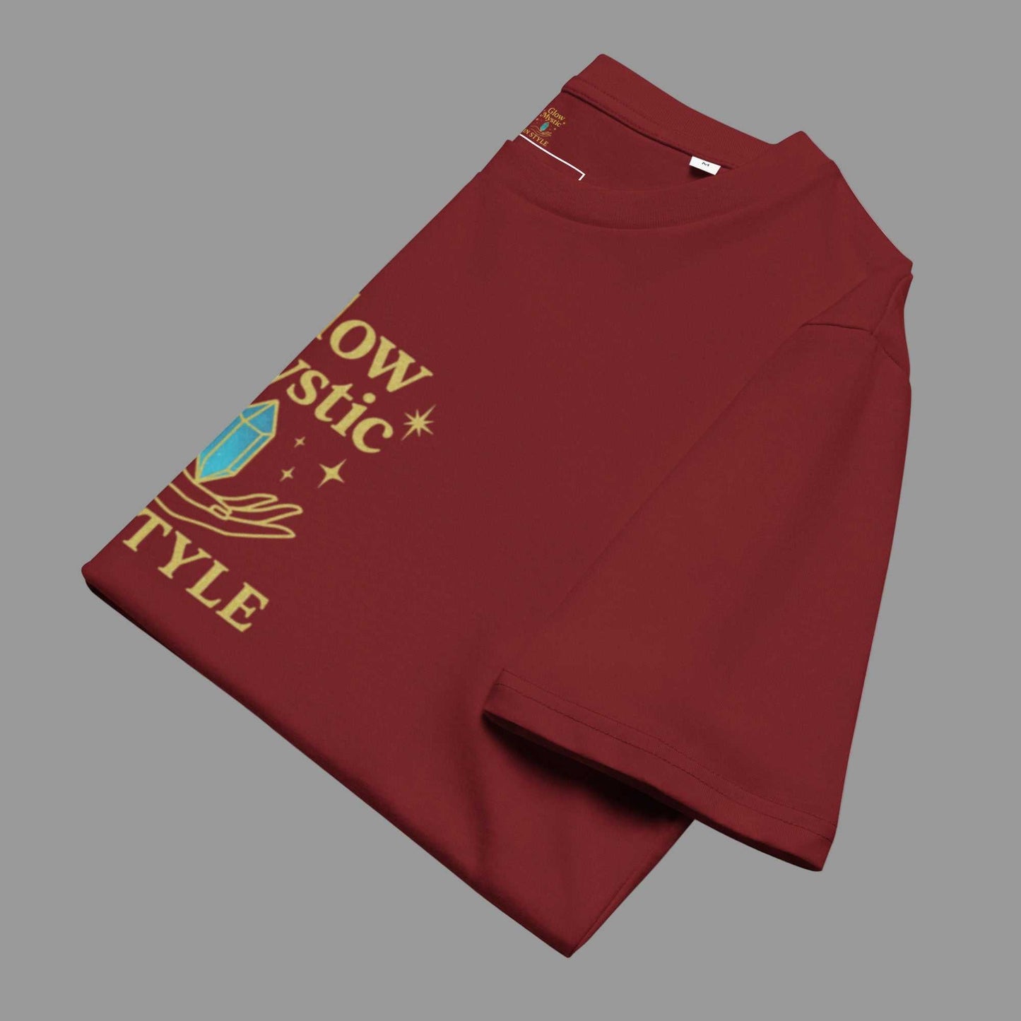 Folded maroon Glow Mystic in Style organic cotton t-shirt with gold logo and crystal design on front