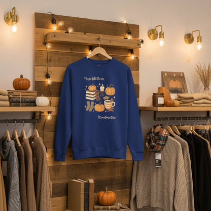 Blue Autumn Magic Classic Sweatshirt with pumpkin and cozy fall design hanging in a warm, decorated autumn clothing store setting