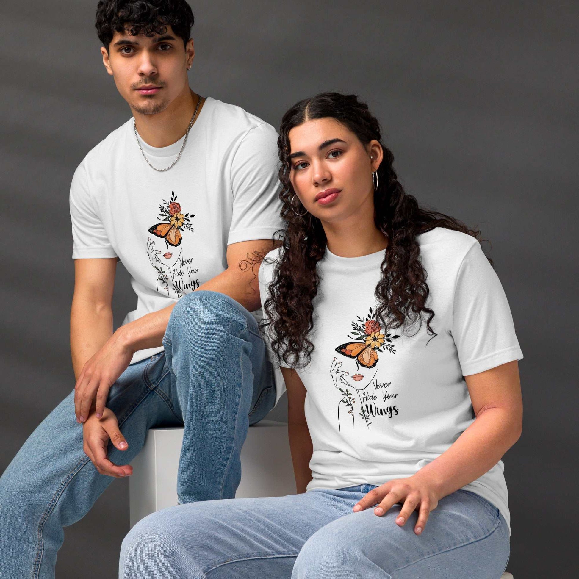 Unisex models wearing white Butterfly Graphic Organic Cotton T Shirts with butterfly and floral design sitting on stools against gray background