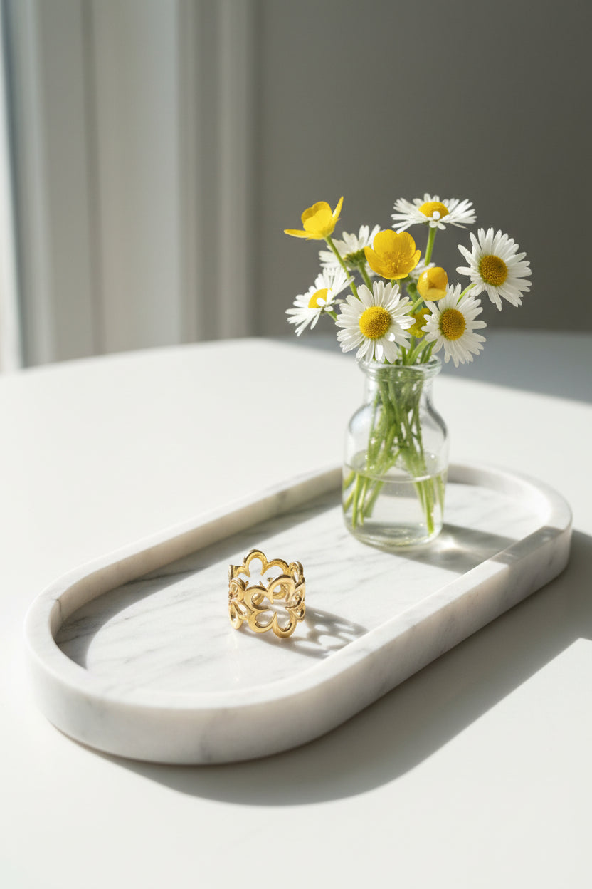 Vijf bloemen ring op een marmeren schaal met een vaasje bloemen ernaast gepresenteerd.
