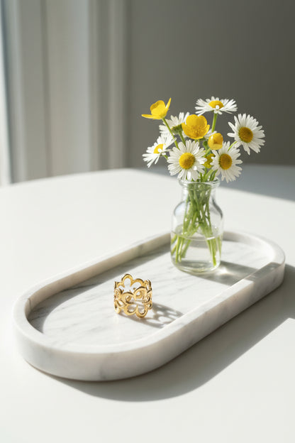 Vijf bloemen ring op een marmeren schaal met een vaasje bloemen ernaast gepresenteerd.