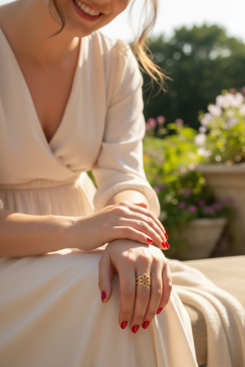 Een lifestyle foto van de goudkleurige opengewerkte bloemenring, elegant gedragen door een model om de vinger in een sfeervolle, zonnige en warme setting.