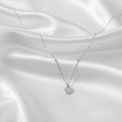 “Vriendinnen ketting zilver met ronde bedel op satijnen achtergrond”