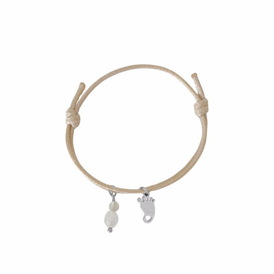 Studiofoto van een beige waxkoord armbandje met een zilverkleurige babyvoetje-bedel en edelstenen, getoond op een witte achtergrond."