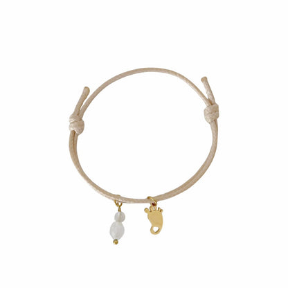 "Studiofoto van een beige waxkoord armbandje met een goudkleurige babyvoetje-bedel en edelstenen, getoond op een witte achtergrond."