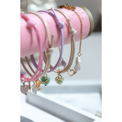 "Close-up van een collectie waxkoord armbandjes met goudkleurige bedels, stijlvol bij elkaar gefotografeerd."
