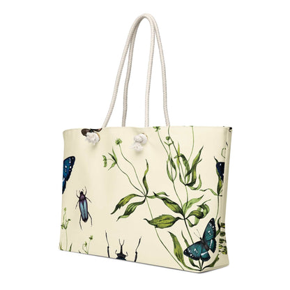 Oversized weekender bag with vintage botanical artwork featuring butterflies and beetles, cream background, and rope handles