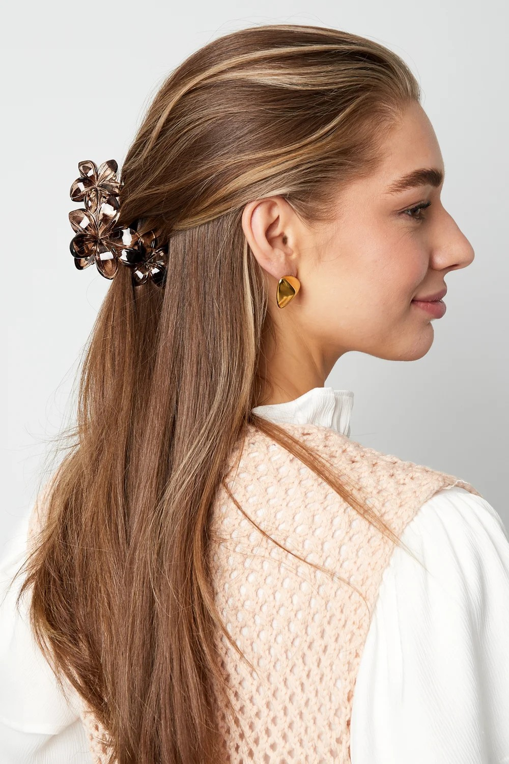 Model draagt grote smokey bruine bloemen haarklem in half-opgestoken haar