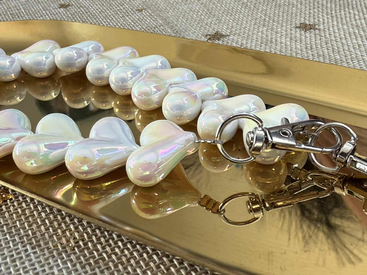 Wit marmeren acryl kralen hartjes koord van Glow Mystic in Style op een goudkleurige schaal.