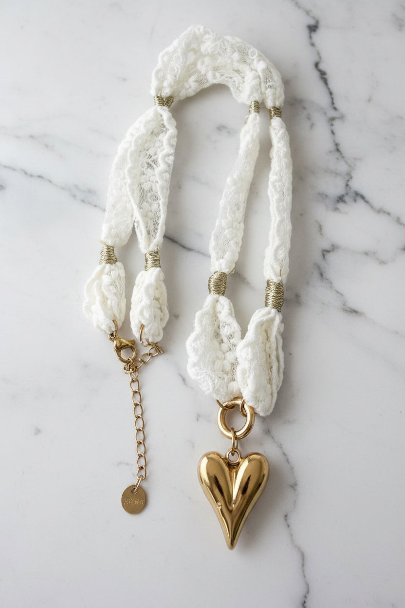 Close-up shot van de witte kanten choker met goud hart hanger gepresenteerd op een marmeren plaat
