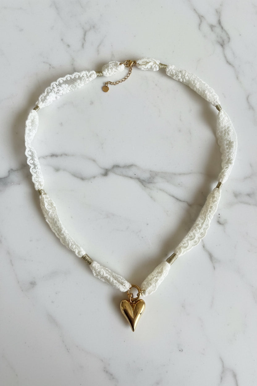 close up van de kanten choker ketting met rvs hart hanger op een marmeren plaat.