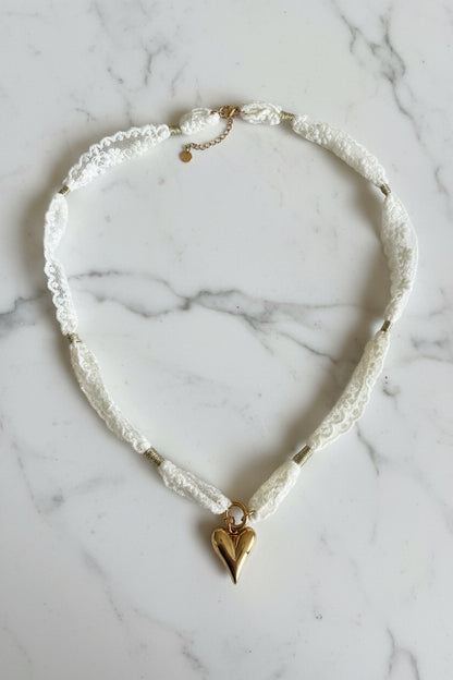 close up van de kanten choker ketting met rvs hart hanger op een marmeren plaat.